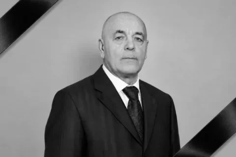 Чорно-білий портрет лисого чоловіка в костюмі з траурними стрічками